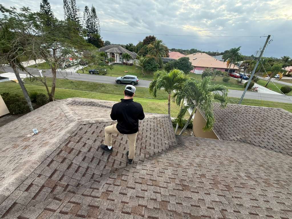 Inspector on ladder checking shingles, Florida home